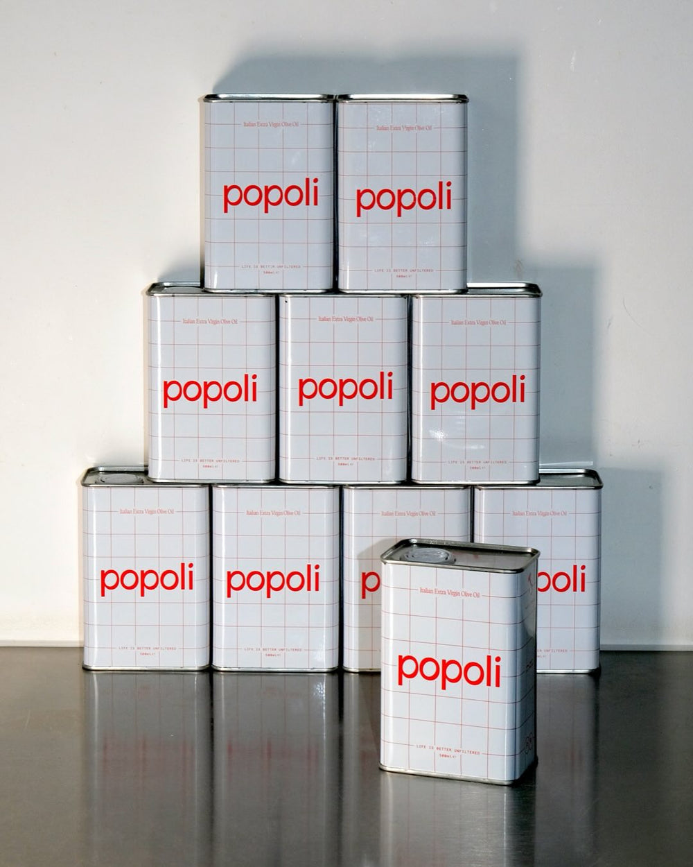 Stack of Popoli tins on a reflective surface with a white background